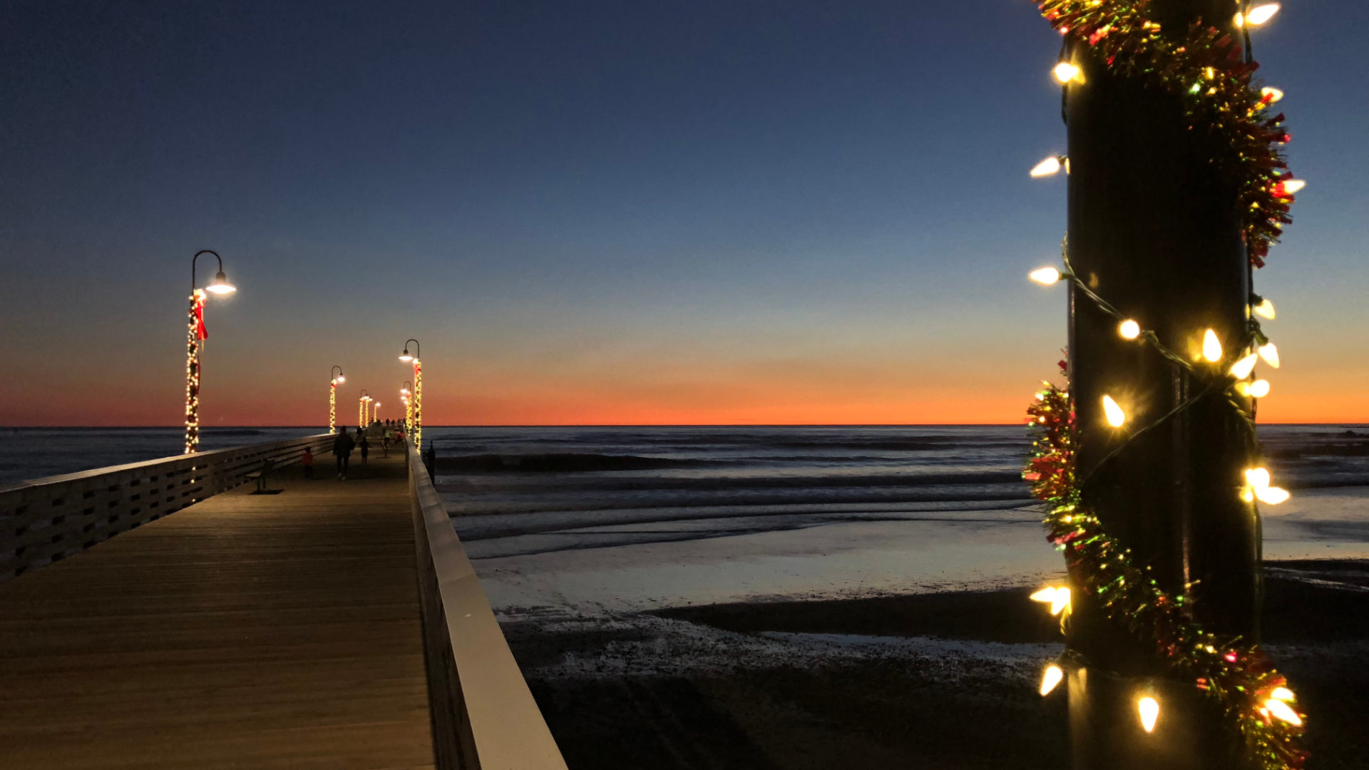 Cayucos Pier decorated with Christmas lights at sunset